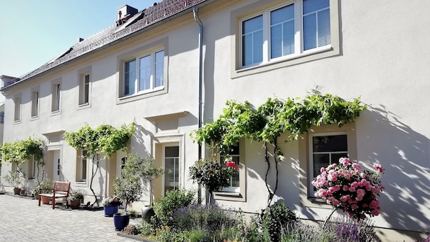 A building with a tiled roof, multiple windows, and a paved walkway. - Apartment "Blütezeit"- Ferienhof Gräfe restored 3-sided farm with pool & sauna (Meißen)