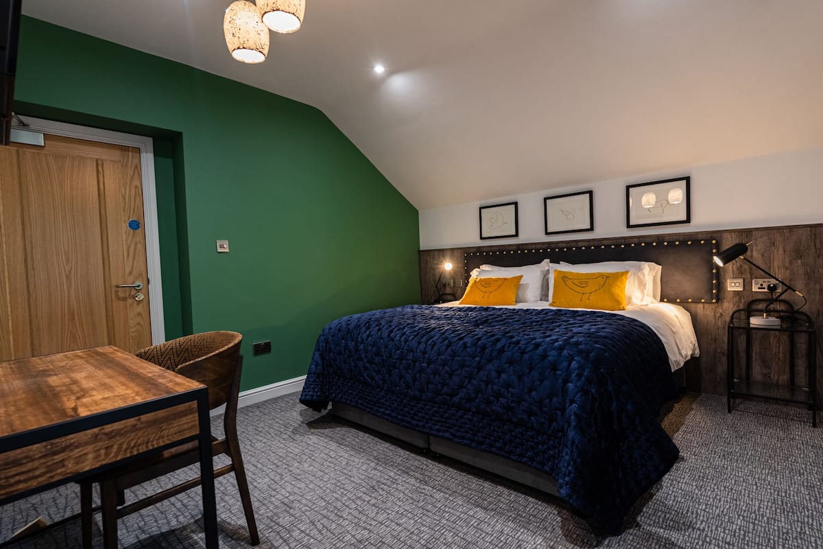 A bedroom with a bed, a wooden table, and a chair.