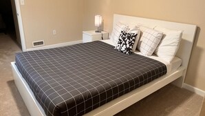 A bedroom with a bed, white headboard, and a nightstand with a lamp. - A Home A Way from your Home with 3-bedroom & 2 bathroom with free parking  (Portland)