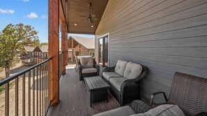 A covered outdoor deck with wicker furniture, a ceiling fan, and a view of neighboring buildings. - Private HotTub - Pool Front - Boat Slip Included (Branson)