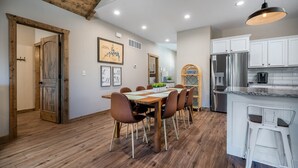 A modern kitchen with white cabinets, stainless steel appliances, and a wooden dining table with chairs. - Private HotTub - Pool Front - Boat Slip Included (Branson)