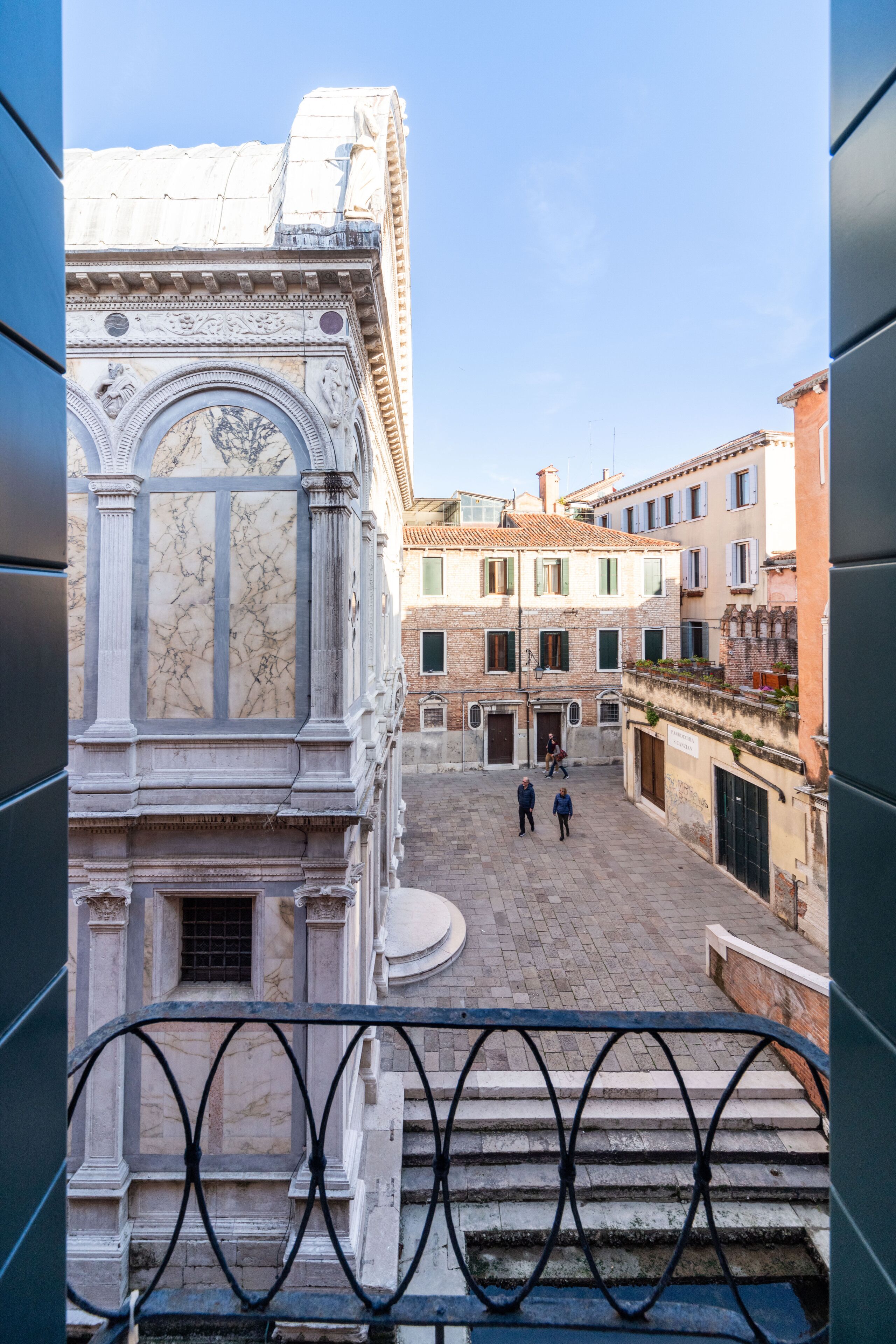 A courtyard with classical architecture, including a marble facade and a staircase leading to an upper level.