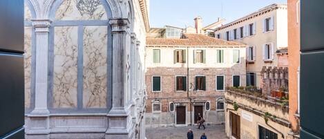 A courtyard with classical architecture, including a marble facade and a staircase leading to an upper level.
