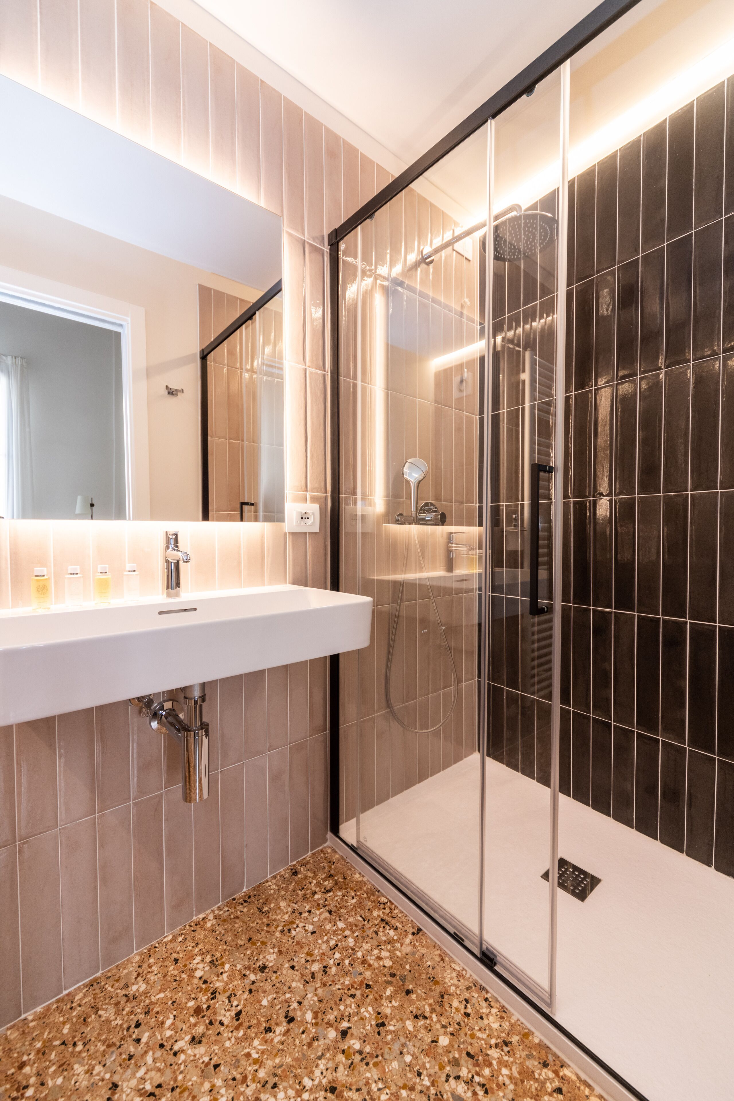 A modern bathroom with a glass-enclosed shower, a white sink, and a mirror above it.