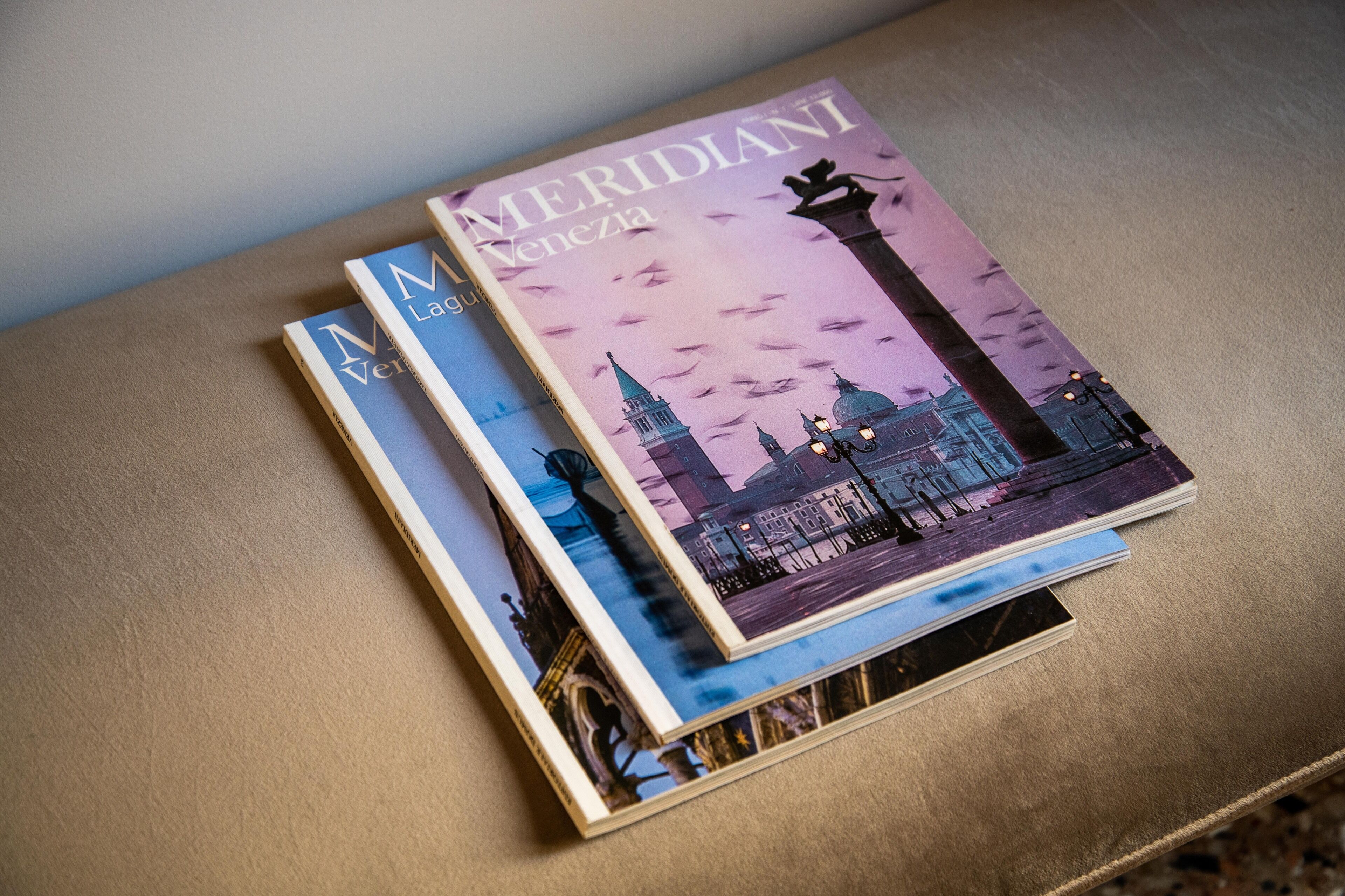 Deux livres intitulés « Meridiani Venezia » et « L’Italia » sont posés sur une surface marron.