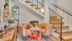 A staircase with wooden steps and metal railings, a small table with a vase and magazine, and two armchairs. - Casa Llibertat (Lliber)
