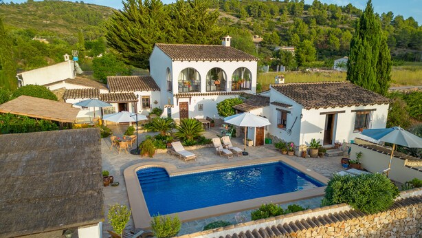 A villa with a swimming pool, outdoor seating, and a stone wall surrounding the property. - Casa Llibertat (Lliber)