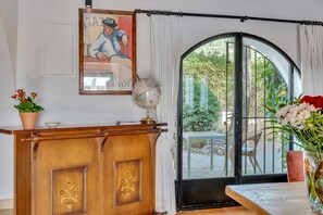 A wooden desk with a globe and a framed painting, a window with curtains, and a vase with flowers. - Casa Llibertat (Lliber)