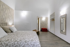 Une chambre à coucher moderne avec un grand lit, un banc en bois, un tabouret rouge et une armoire avec un miroir.