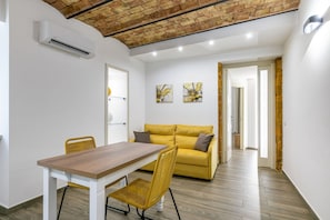 Un intérieur moderne avec une table à manger, un canapé jaune et des œuvres d’art accrochées aux murs.