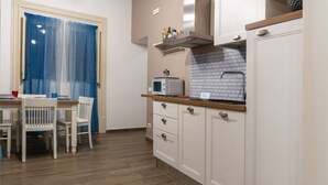 A small kitchen with a microwave, a sink, and a window with blue curtains. - GuestHost - Charming 55 sqm apartment, for 4 people, located on the 1st floor of a renovated period building (NO lift; 38 steps). The property is located in the center of Palermo (Restricted-Traffic Area), a few steps from the main attractions of the cit (Palermo)