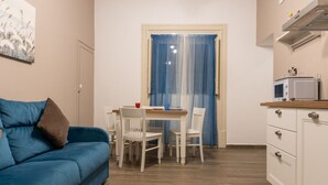 A compact living space with a blue sofa, a dining table with chairs, a kitchen area with a microwave, and a door with blue curtains. - GuestHost - Charming 55 sqm apartment, for 4 people, located on the 1st floor of a renovated period building (NO lift; 38 steps). The property is located in the center of Palermo (Restricted-Traffic Area), a few steps from the main attractions of the cit (Palermo)