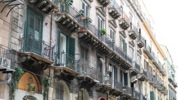 A multi-story building with balconies, a sign for a bar, and a blue sign indicating a public restroom. - GuestHost - Charming 55 sqm apartment, for 4 people, located on the 1st floor of a renovated period building (NO lift; 38 steps). The property is located in the center of Palermo (Restricted-Traffic Area), a few steps from the main attractions of the cit (Palermo)