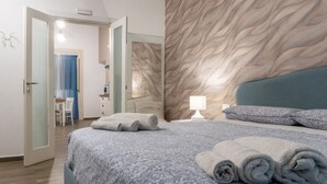 A bedroom with a bed, a nightstand, a lamp, a chair, and a door leading to another room. - GuestHost - Charming 55 sqm apartment, for 4 people, located on the 1st floor of a renovated period building (NO lift; 38 steps). The property is located in the center of Palermo (Restricted-Traffic Area), a few steps from the main attractions of the cit (Palermo)