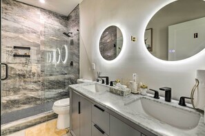 Een moderne badkamer met een groot wastafel, twee spiegels, een douche en een toilet.