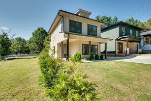 Een tweelaags huis met een overdekte veranda en een verzorgd gazon.