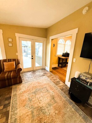A living room with a striped sofa, a patterned rug, a television, and a bookshelf.