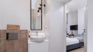 A modern bathroom with a white sink, a mirror, and a wall-mounted light fixture. - Functional Studio | Close to Market Square and Wawel Castle (Kraków)