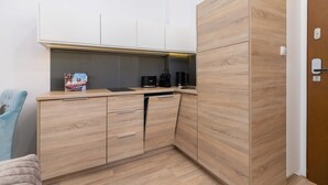 A compact kitchenette with wooden cabinets, a countertop, and a coffee maker. - Functional Studio | Close to Market Square and Wawel Castle (Kraków)