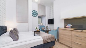 A modern bedroom with a bed, bedside table, and a TV. - Functional Studio | Close to Market Square and Wawel Castle (Kraków)