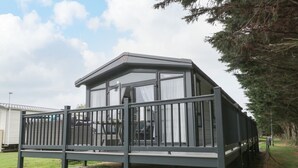 A modern mobile home with a balcony, a covered porch, and a fenced yard. - 59 Finch (Scarborough)