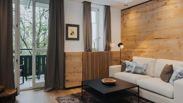A modern living room with a white sofa, a black coffee table, and a wooden accent wall.
