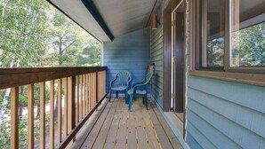 A wooden porch with a railing, two chairs, and a window overlooking a wooded area. - Brookside I B-405 - Sunday River Slopeside Condominium (Newry)