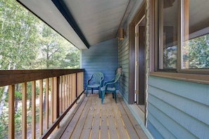 A wooden porch with a railing, two chairs, and a window overlooking a wooded area. - Brookside I B-405 - Sunday River Slopeside Condominium (Newry)