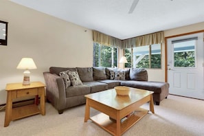 A living room with a sofa, a coffee table, a side table, and a lamp. - Brookside I B-405 - Sunday River Slopeside Condominium (Newry)