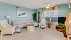 A living room with a sofa, armchairs, a coffee table, a TV, and a ceiling fan.