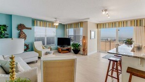 A living room with a sofa, TV, and a balcony with a view.