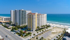 A beachfront hotel with multiple high-rise buildings, a parking lot, and a beach in the background.