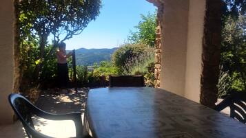 A patio with a table and chairs, a stone wall, and a view of a tree and landscape.