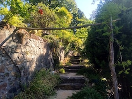 Una escalera de piedra rodeada de abundante vegetación, que asciende por un sendero rocoso.