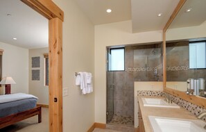 Une salle de bain moderne dotée d’une douche à l’italienne, de deux vasques et d’un grand miroir.