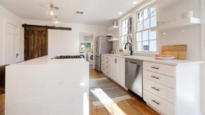 A modern kitchen with a central island, stainless steel appliances, and a large window providing natural light. - Modern luxury with classic Fredricksburg charm just blocks from Main Street (Fredericksburg)