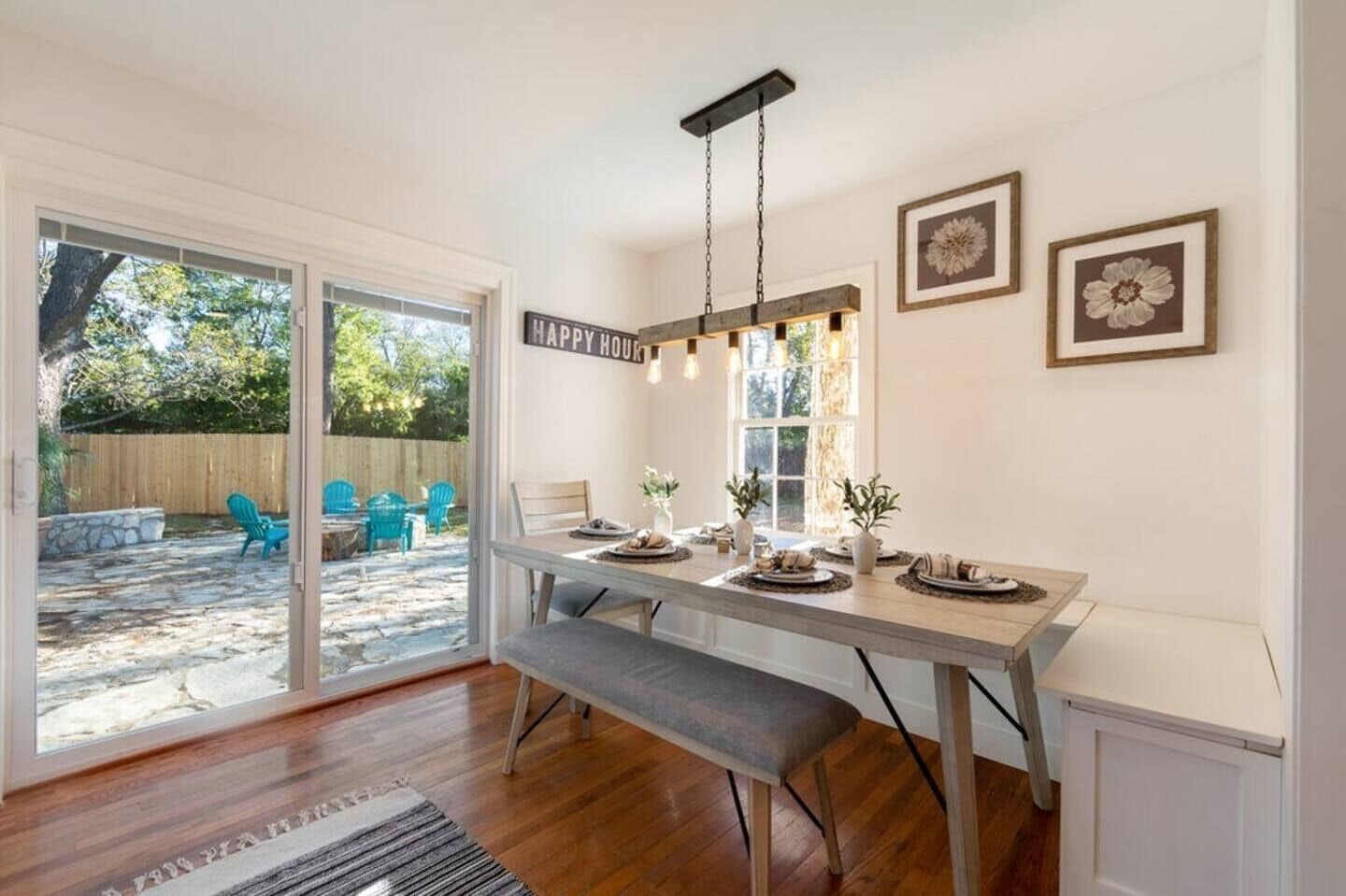 A dining area with a bench, a table set for four, and a 'HAPPY HOUR' sign.