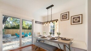 A dining area with a bench, a table set for four, and a 'HAPPY HOUR' sign. - Modern luxury with classic Fredricksburg charm just blocks from Main Street (Fredericksburg)