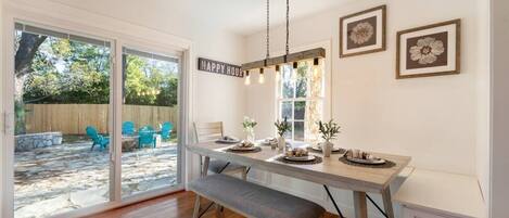 A dining area with a bench, a table set for four, and a 'HAPPY HOUR' sign.