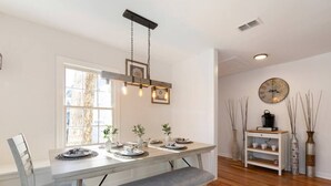 A dining area with a long table, benches, and a hanging light fixture. - Modern luxury with classic Fredricksburg charm just blocks from Main Street (Fredericksburg)