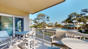 Un balcon avec coin salon extérieur, une piscine et une vue sur la plage et l’océan.