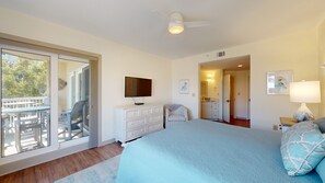 Une chambre à coucher avec un lit, une télévision, une commode, une chaise et un balcon.