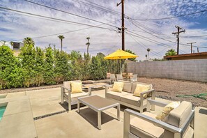 An outdoor patio with a pool, lounge chairs, and a yellow umbrella.