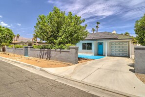 A residential house with a garage, a driveway, and a large tree in the front yard.
