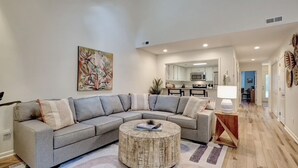 A modern living room with a sectional sofa, a round coffee table, and a painting on the wall. - Convenient to Beach, restaurants, shopping and much more! (Wilmington)