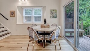 A dining area with a round table and four chairs, a window with blinds, and a staircase. - Convenient to Beach, restaurants, shopping and much more! (Wilmington)