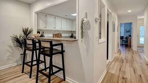 A modern kitchen with white cabinets, a bar stool, and a potted plant. - Convenient to Beach, restaurants, shopping and much more! (Wilmington)