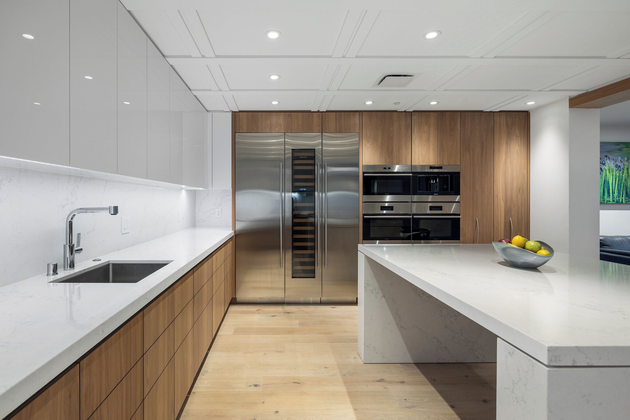 Una cocina moderna con electrodomésticos de acero inoxidable, armarios de madera y encimera de mármol.