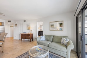 A living room with a sofa, a coffee table, and a dining area with chairs and a table.