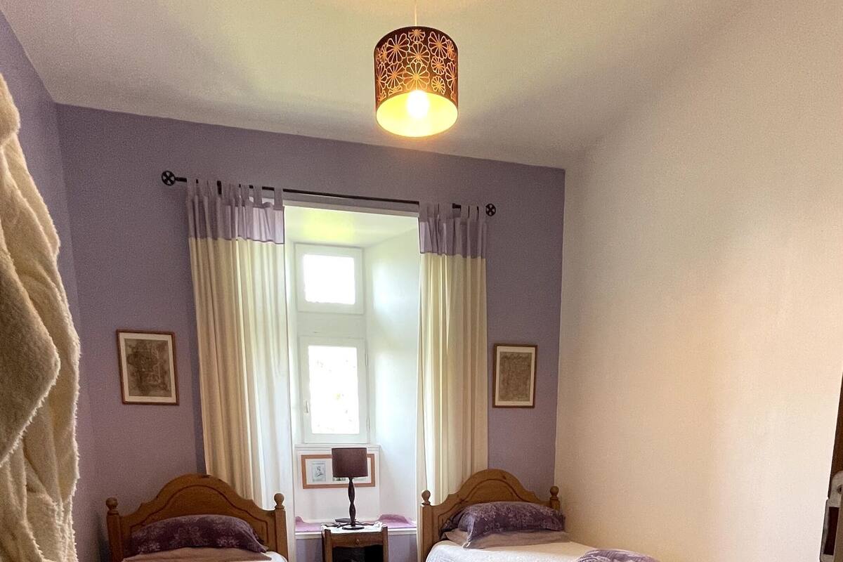 Een slaapkamer met twee bedden, een bureau, een stoel en een hanglamp.